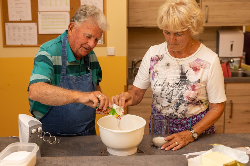 zwei ältere Menschen backen einen Kuchen zusammen